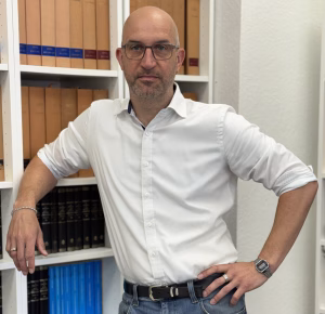 Rechtsanwalt und Fachanwalt für Strafrecht Constantin W. Kirschbaum vor dem Bücherregal in seiner Kanzlei